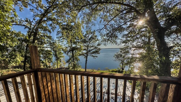 Una terraza de madera con vista a un lago y árboles.