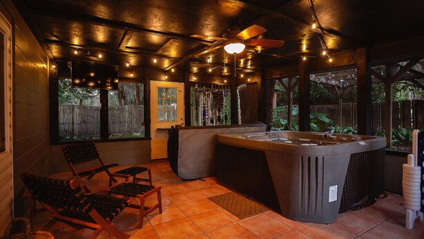A hot tub area with a ceiling fan, string lights, and wooden deck chairs. - New! Saltwater pool home with hot tub, game room, and outdoor games! (Gainesville)