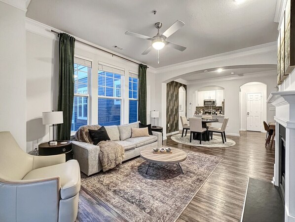 A spacious living room with a sofa, coffee table, and a dining area with chairs and a table.