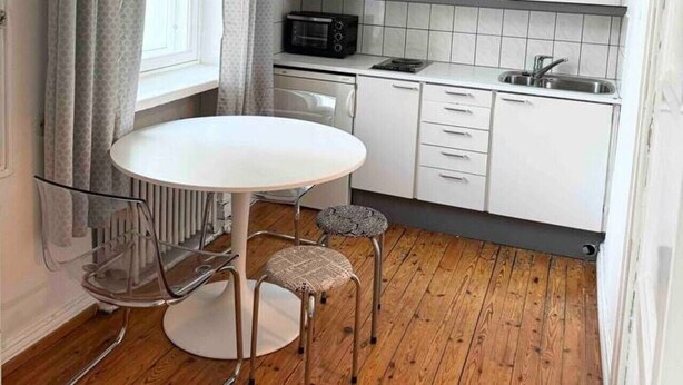 A compact kitchen with white cabinets, a round dining table, and a small stool. - Central stay in Helsinki (Helsinki)