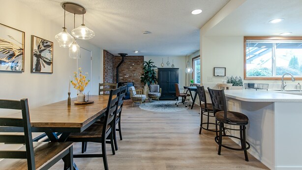 A spacious kitchen with a large island, wooden dining table, and modern pendant lighting. - Cheerful, Comfortable and Convenient 3 Bedroom Home (Eugene)