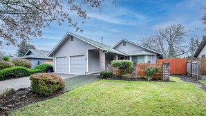 A residential house with a garage, a well-maintained lawn, and a wooden fence. - Cheerful, Comfortable and Convenient 3 Bedroom Home (Eugene)