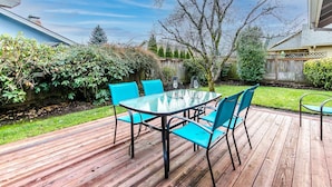 A wooden deck with a glass table and four chairs. - Cheerful, Comfortable and Convenient 3 Bedroom Home (Eugene)
