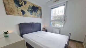 Un dormitorio con cama, un mapa del mundo en la pared, una ventana y un radiador.