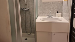 Un baño con ducha, lavabo y espejo.