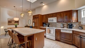 A modern kitchen with wooden cabinets, a central island, and pendant lighting. - Sedona Retreat W/ Tesla Mobile Charger (Sedona)