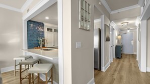 Une cuisine moderne avec un mur d’accent bleu, un réfrigérateur en acier inoxydable et un coin bar avec des tabourets.