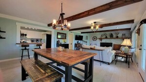 Un salón amplio con una mesa de comedor de madera, una chimenea y un televisor montado en la pared.
