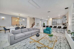 A spacious living area with a sofa, a coffee table, and a kitchen in the background.