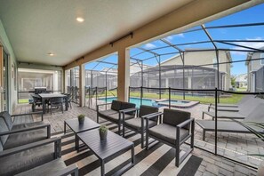 An outdoor patio with seating, a pool, and a view of neighboring houses.