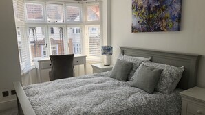 Een slaapkamer met een bed, een bureau en een stoel.