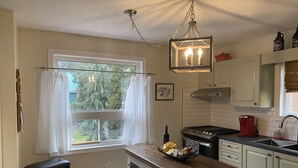 Une cuisine avec une fenêtre, un lustre et une machine à café.