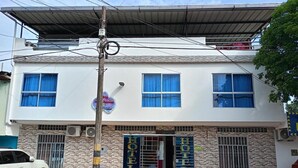 A two-story hotel with a stone facade and blue-framed windows. - Hotel Bella Orquidea (Neiva)