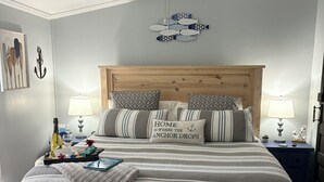 A neatly arranged bedroom with a wooden bed, two bedside tables, a ceiling fan, and a wall-mounted fish decoration. - Lakefront Property 
Fish, Cook and EAT!
Swim, Float, Relax (Sparta)