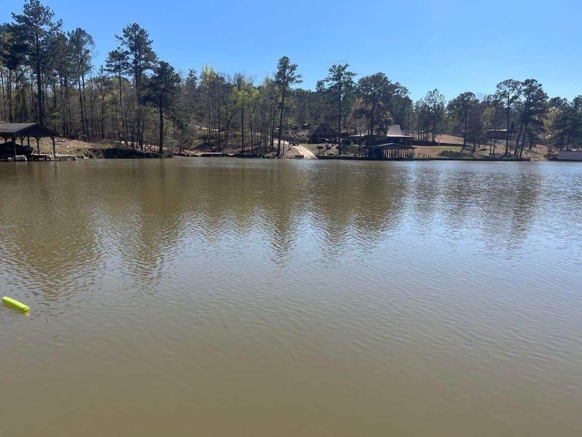 A calm lake with a wooden dock and a gazebo.