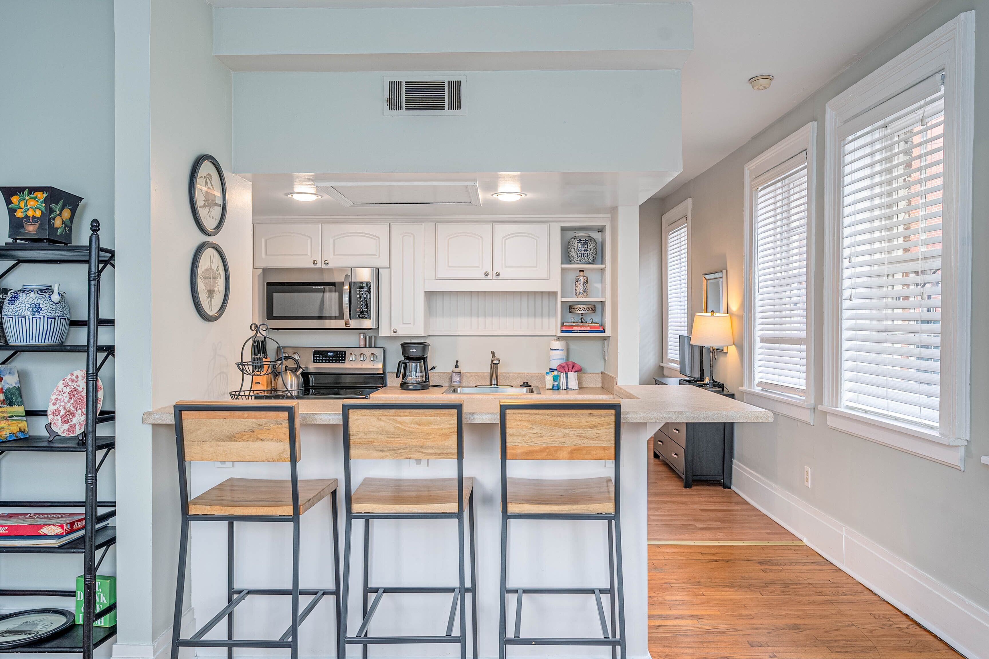 A modern kitchen with white cabinetry, a central island with bar stools, and a built-in oven.