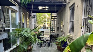 A narrow alleyway with potted plants, a small table, and chairs, leading to a building entrance. - Location! Perfect Downtown Savannah Couples Getaway 1 bed 1 bath (Savannah)