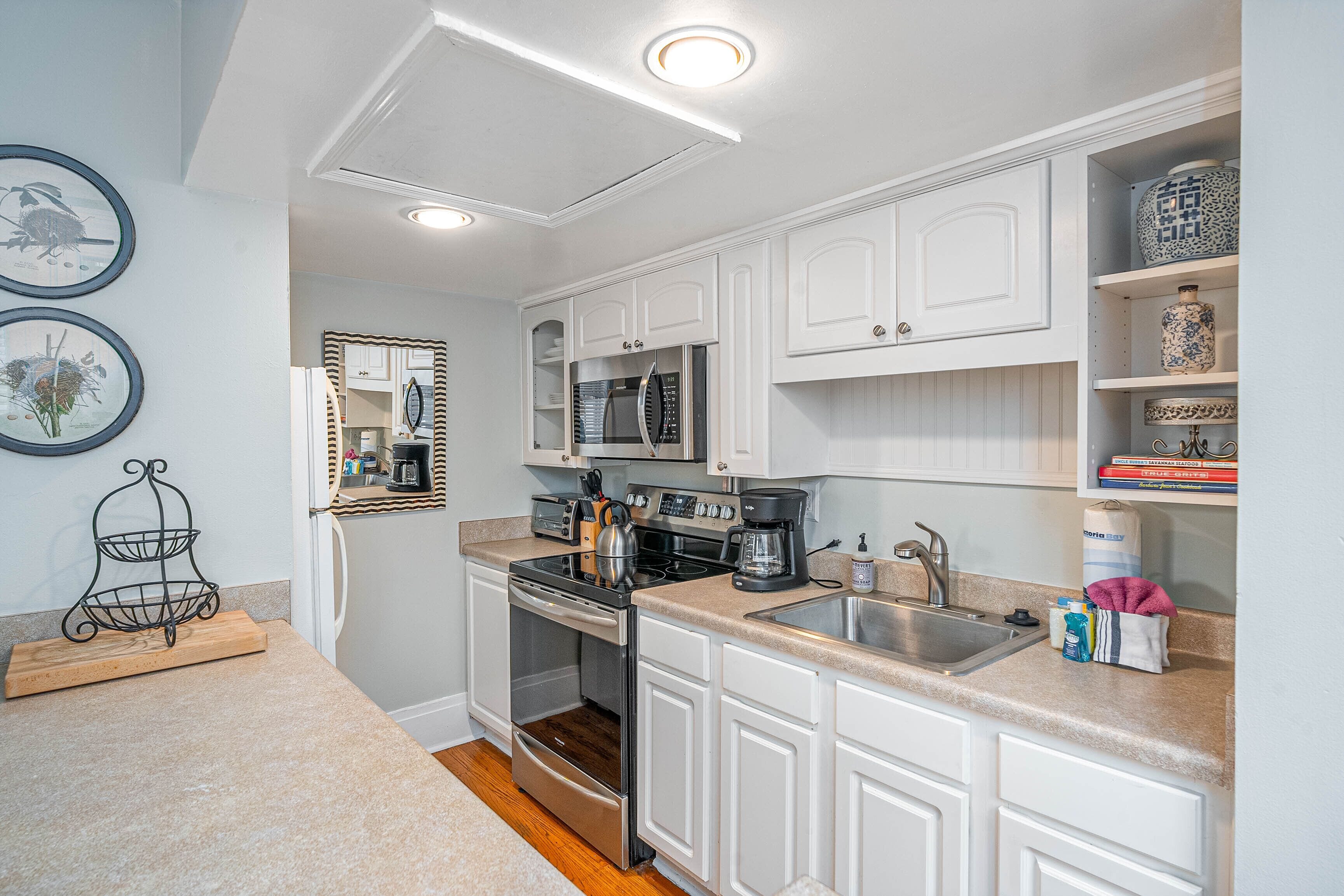 A modern kitchen with white cabinetry, stainless steel appliances, and a built-in oven.