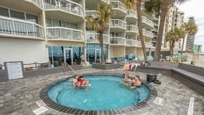 A swimming pool area with a pool, lounge chairs, and a building with balconies. - Oceanfront Resort - Hot Tub, Heated Pool, Balcony (Murrells Inlet)