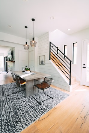 A modern kitchen with a wooden island, black chairs, and pendant lights.