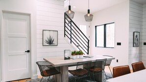 A modern dining area with a wooden table, black wire chairs, and a patterned rug.