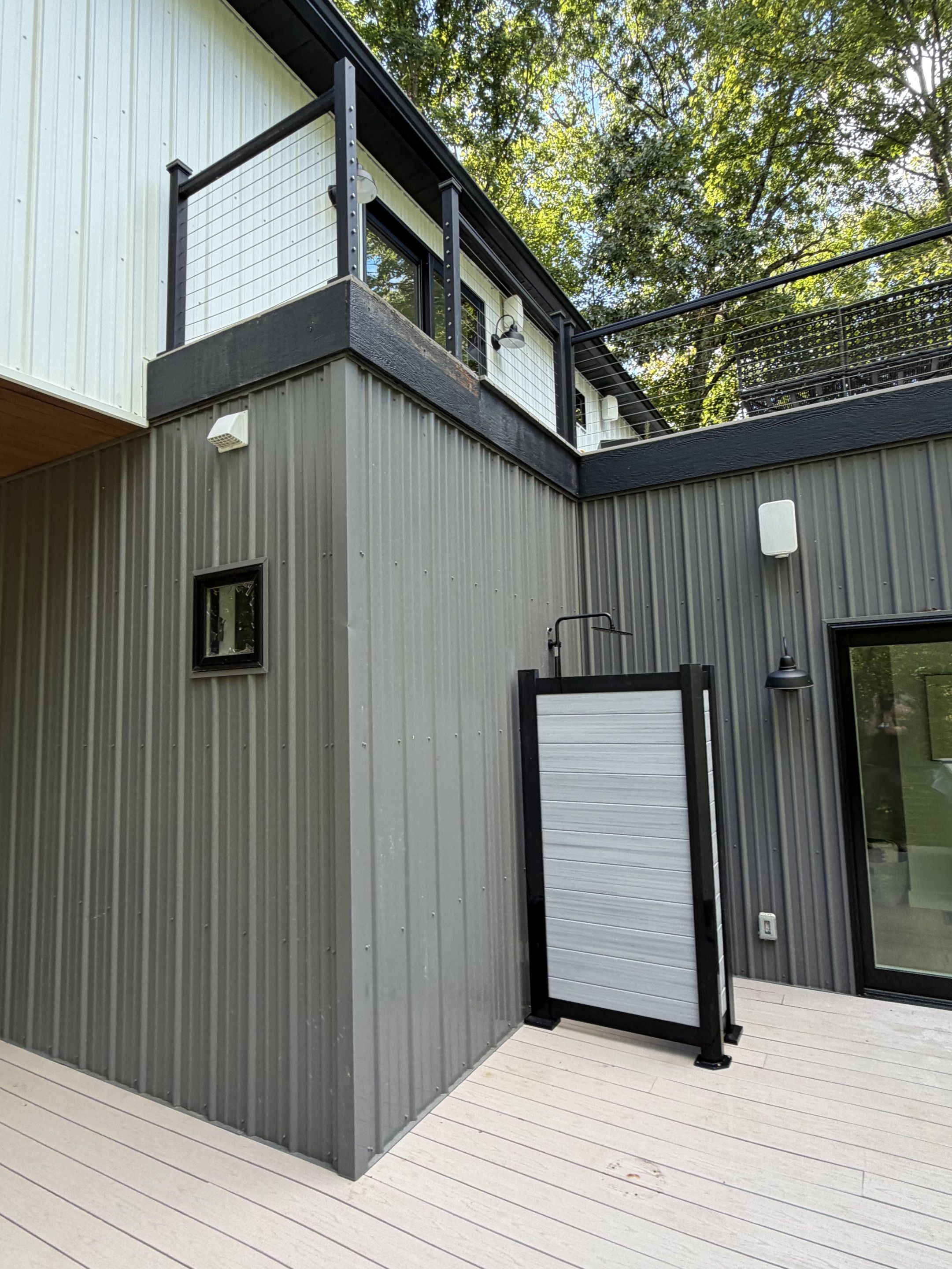 A modern building with a metal exterior, a covered deck, and a sliding door.