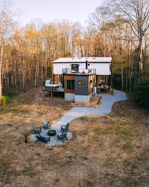 Una cabaña moderna con terraza, asientos al aire libre y una chimenea.