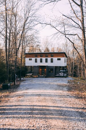 Une maison moderne à deux étages, dotée d’un toit plat et entourée d’arbres.