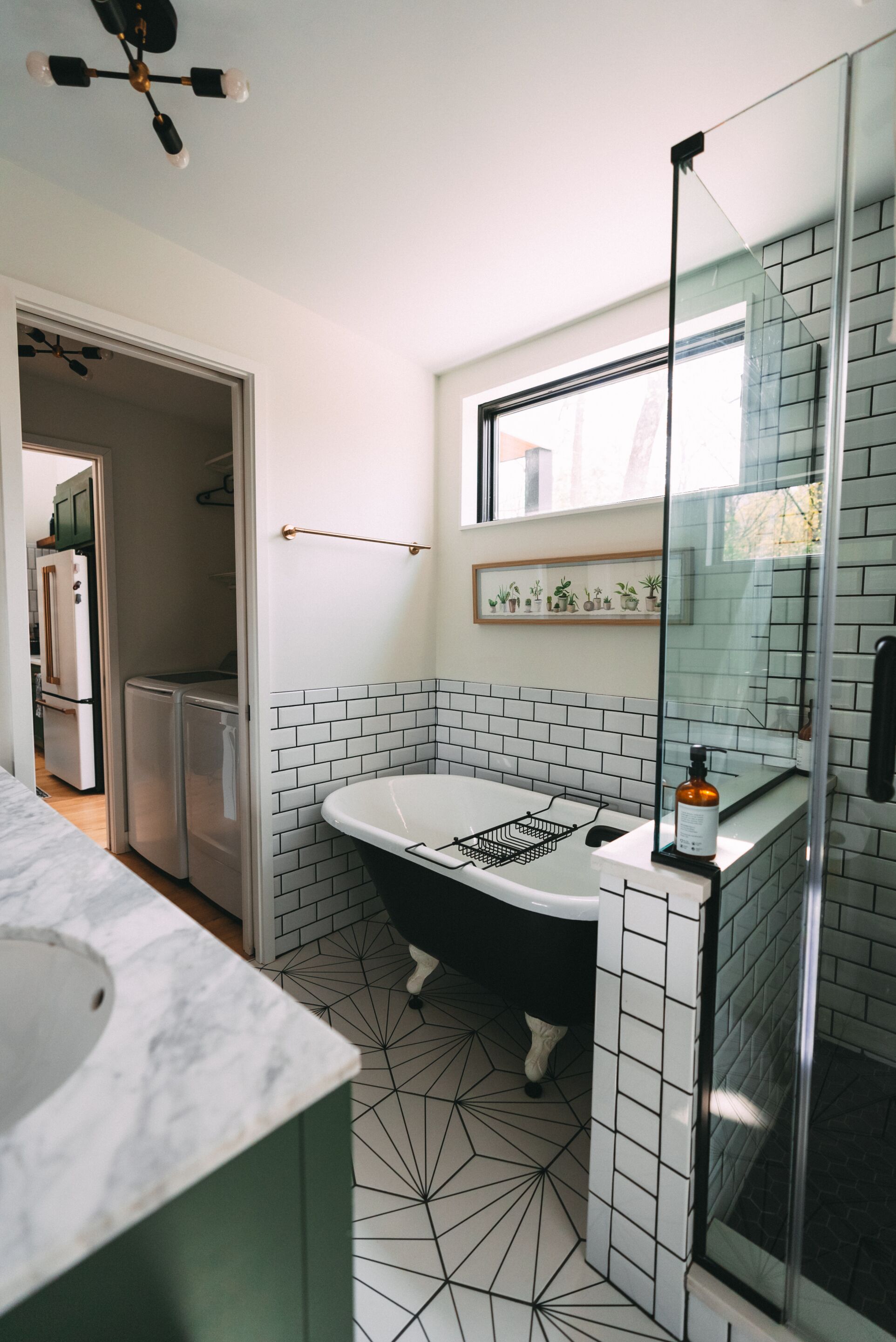 A modern bathroom with a freestanding bathtub, a glass shower enclosure, and a tiled floor with a geometric pattern.