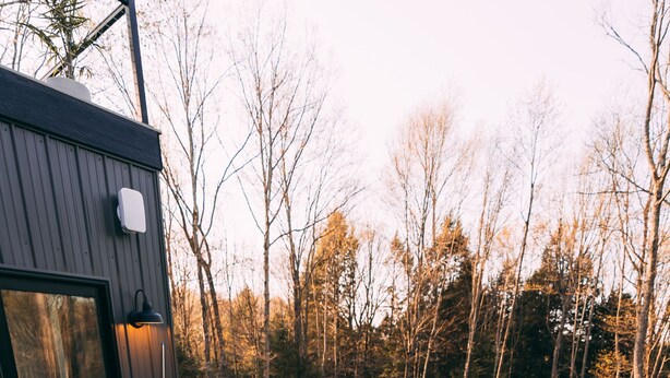 A hot tub on a wooden deck with a glass door and a view of trees.