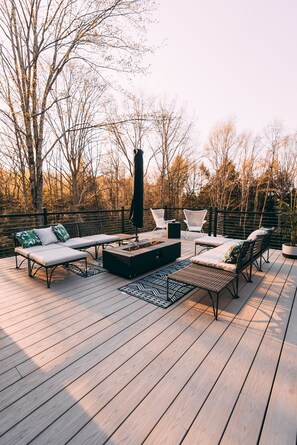 Une terrasse avec coin salon extérieur, comprenant des canapés et des fauteuils, ainsi qu’un foyer.