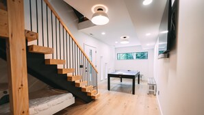 Een modern interieur met een houten trap, een tafeltennistafel en een groot raam.