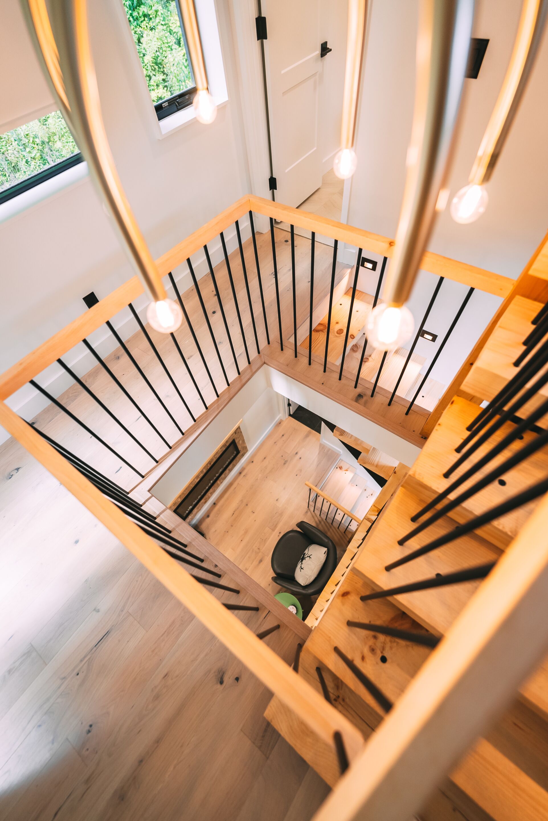 Un interior moderno con una escalera de madera, una chimenea y vistas al exterior.