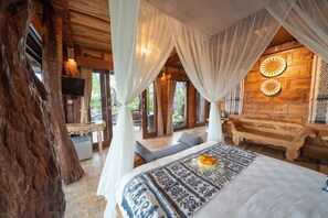 Um quarto de madeira com uma cama, um banco e um tronco de árvore grande.