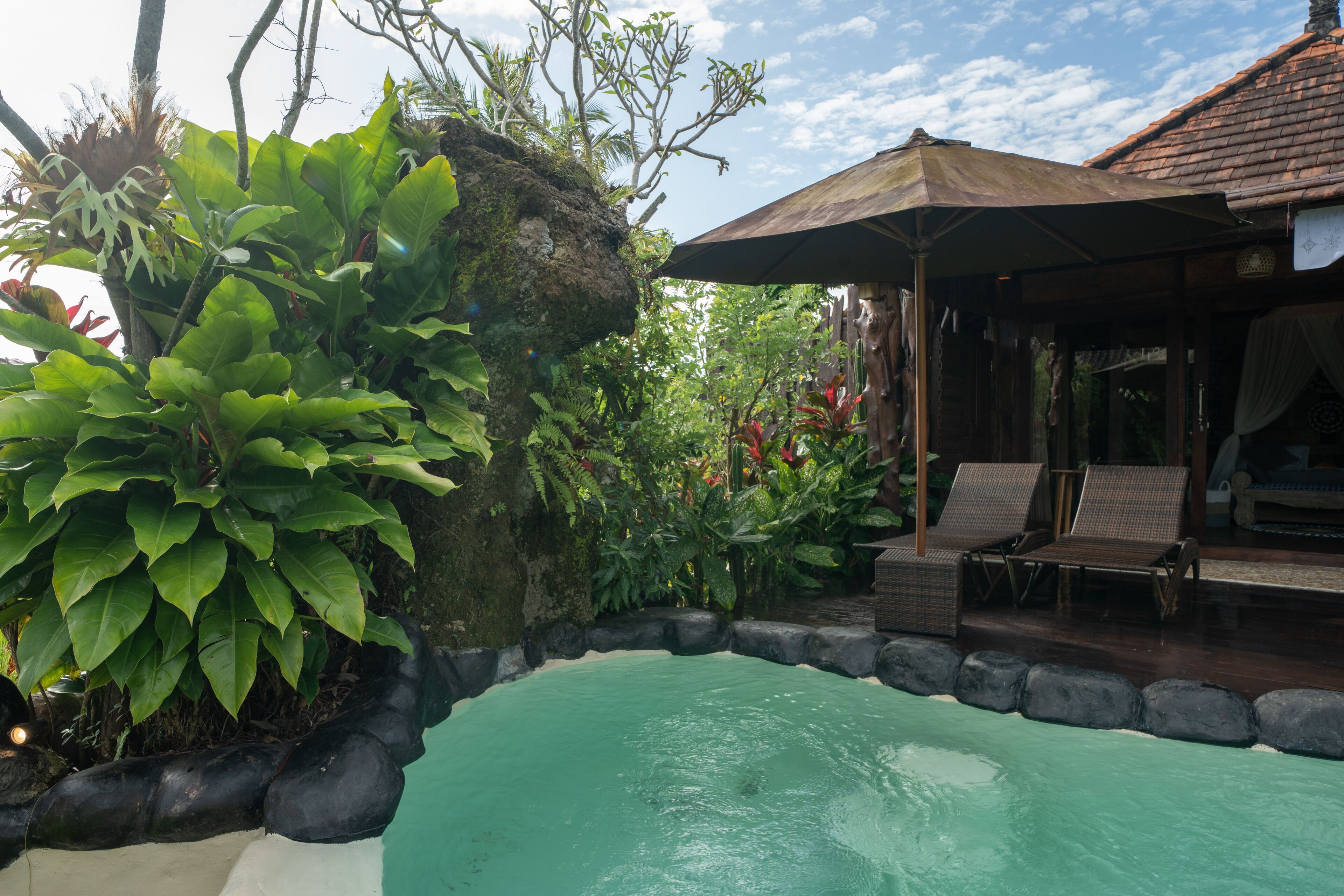 A pool area with lounge chairs and a covered seating area.