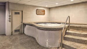 A spa area with a hot tub, a sign listing jacuzzi rules, and a door with a vent.