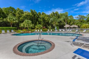 A swimming pool with lounge chairs and a hot tub.