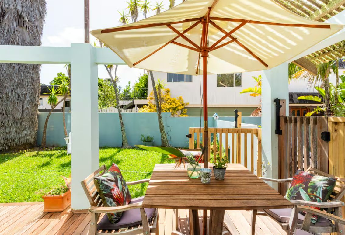 A wooden deck with a table and chairs, an umbrella, and potted plants.