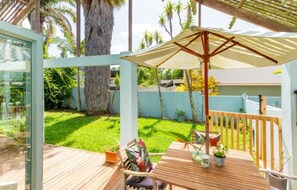 A wooden deck with a table and chairs, a large umbrella, and a glass enclosure. - Great-Located North Shore Room in Tropical Garden – Close to the Beach 🌴🌊 (Auckland)