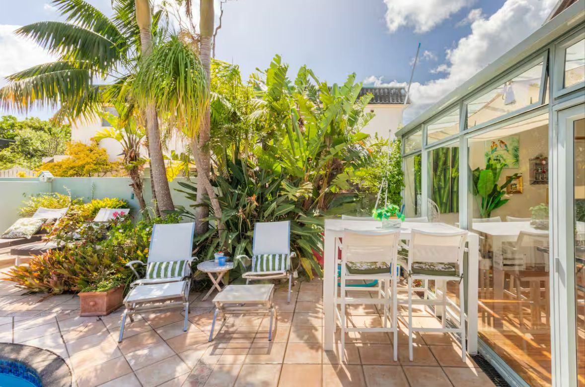 An outdoor patio with chairs, a table, and a glass enclosure with a view.