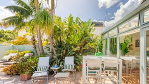 En udendørs terrasse med stole, et bord og et glashus med udsigt.
