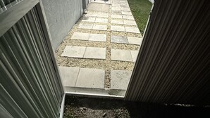 Laatoitettu patio, jossa on valkoinen aita ja pieni nurmialue.