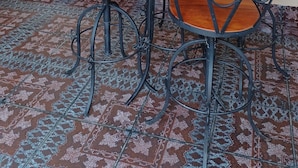 Une table ronde sur laquelle repose un panier en osier, entourée de quatre chaises dotées d’une structure en métal et d’un siège en bois.