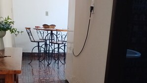 Un espace patio carrelé avec une table et des chaises, une prise électrique sur le mur et une plante en pot.