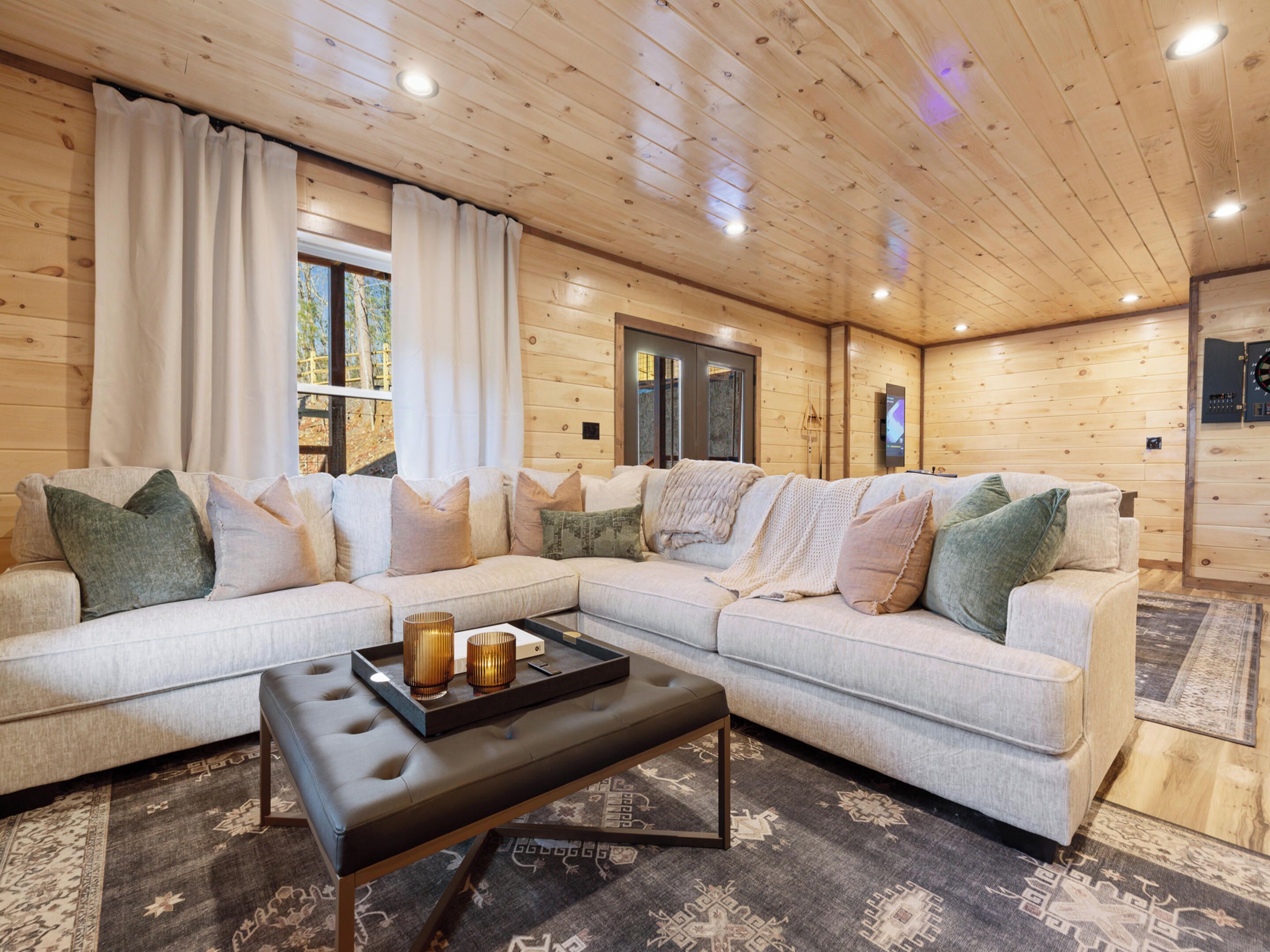 A cozy living room with a sectional sofa, a coffee table, and a wooden ceiling.