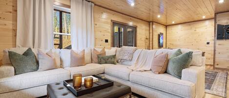 A cozy living room with a sectional sofa, a coffee table, and a wooden ceiling.