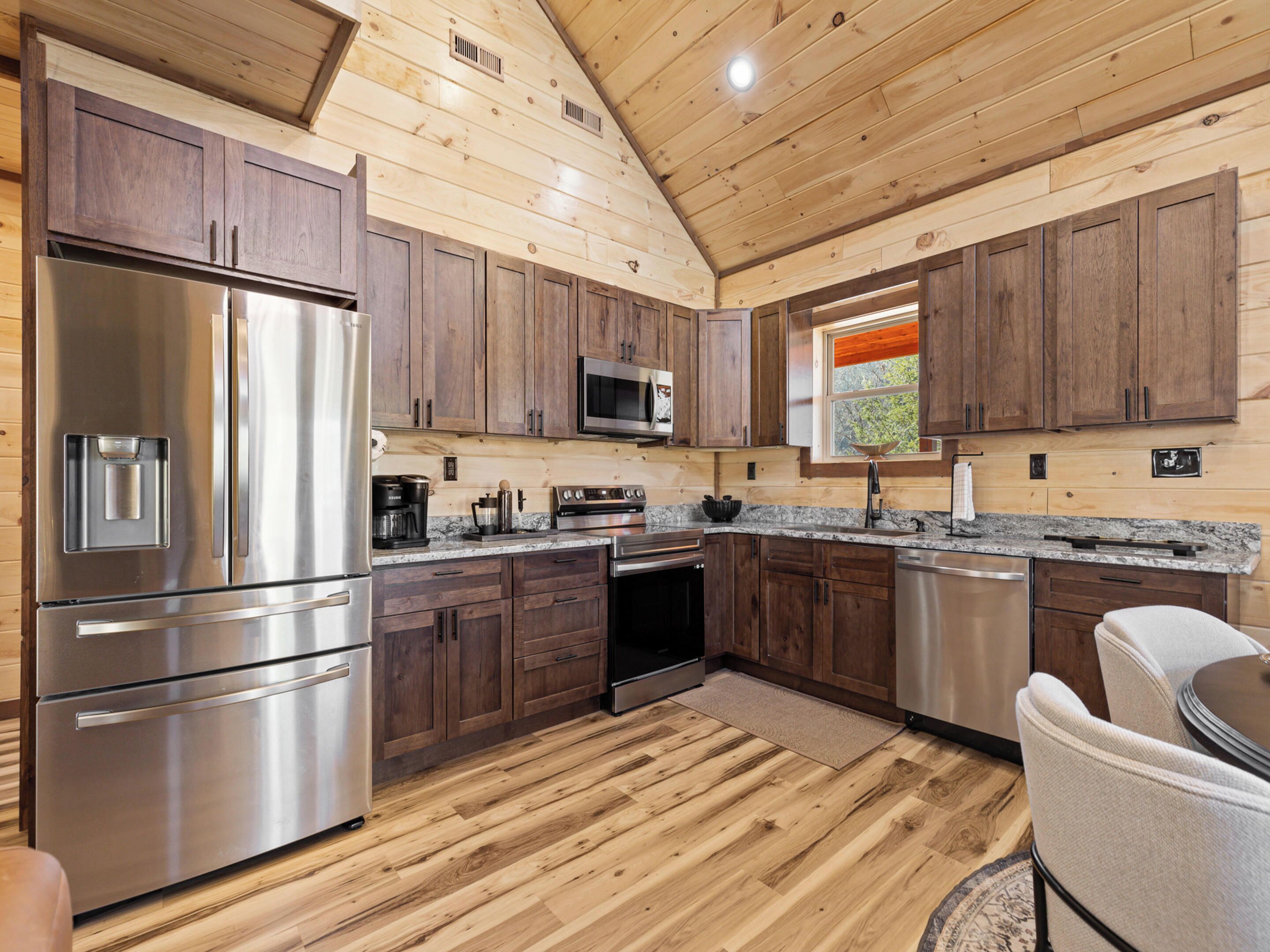 A modern kitchen with wooden cabinets, stainless steel appliances, and a wooden floor.