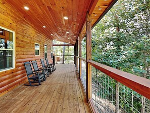 A wooden cabin with a covered porch, wooden flooring, and a view of the surrounding forest. - Mountain Ventures by Jackson Mountain Rentals (Pigeon Forge)
