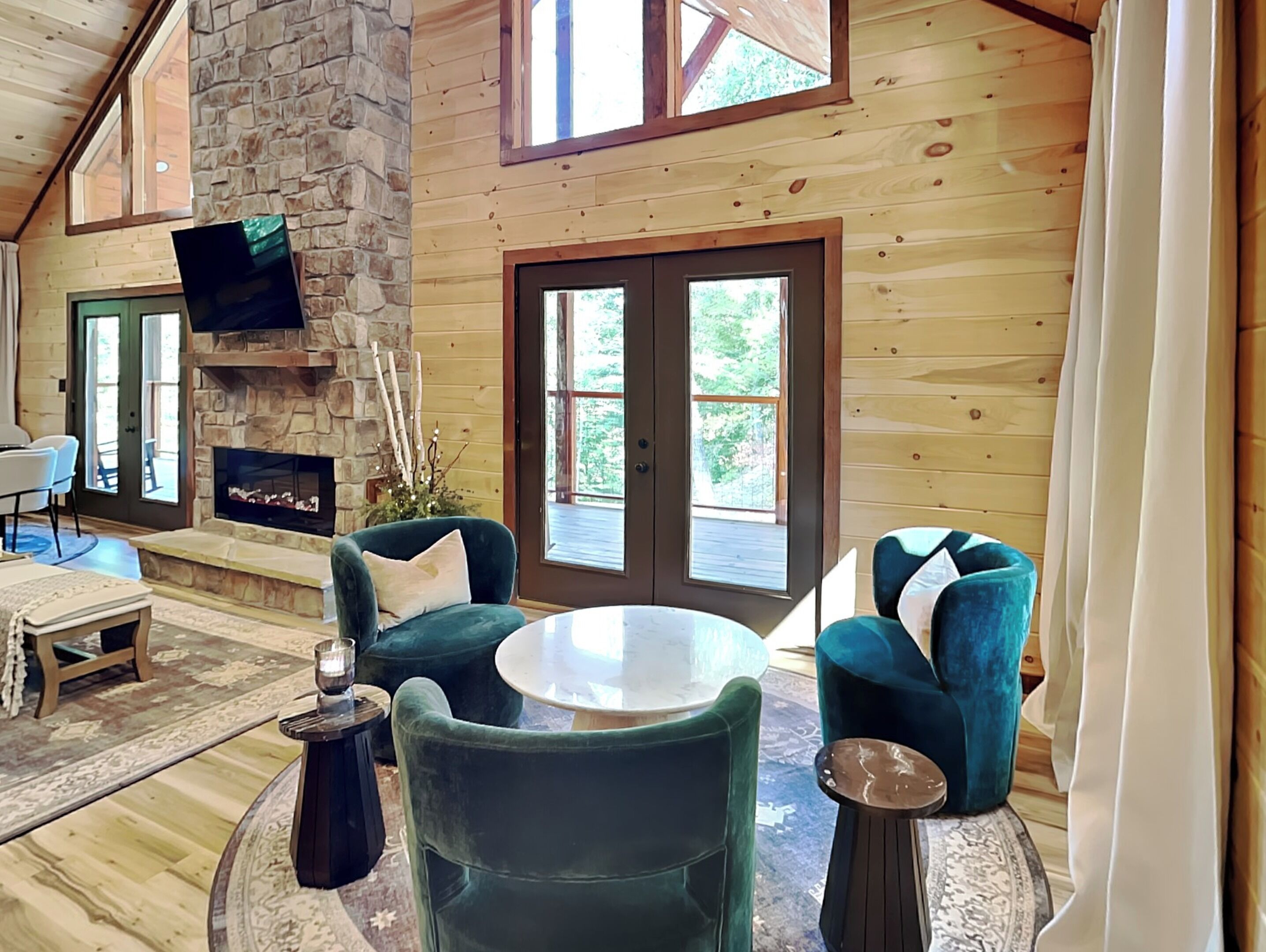 Interior acogedor de una cabaña con chimenea de piedra, paredes de madera y un ventanal grande.