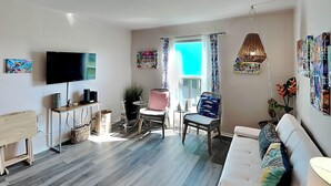 Un salon moderne avec un téléviseur à écran plat, un canapé, une table à manger et une chaise.